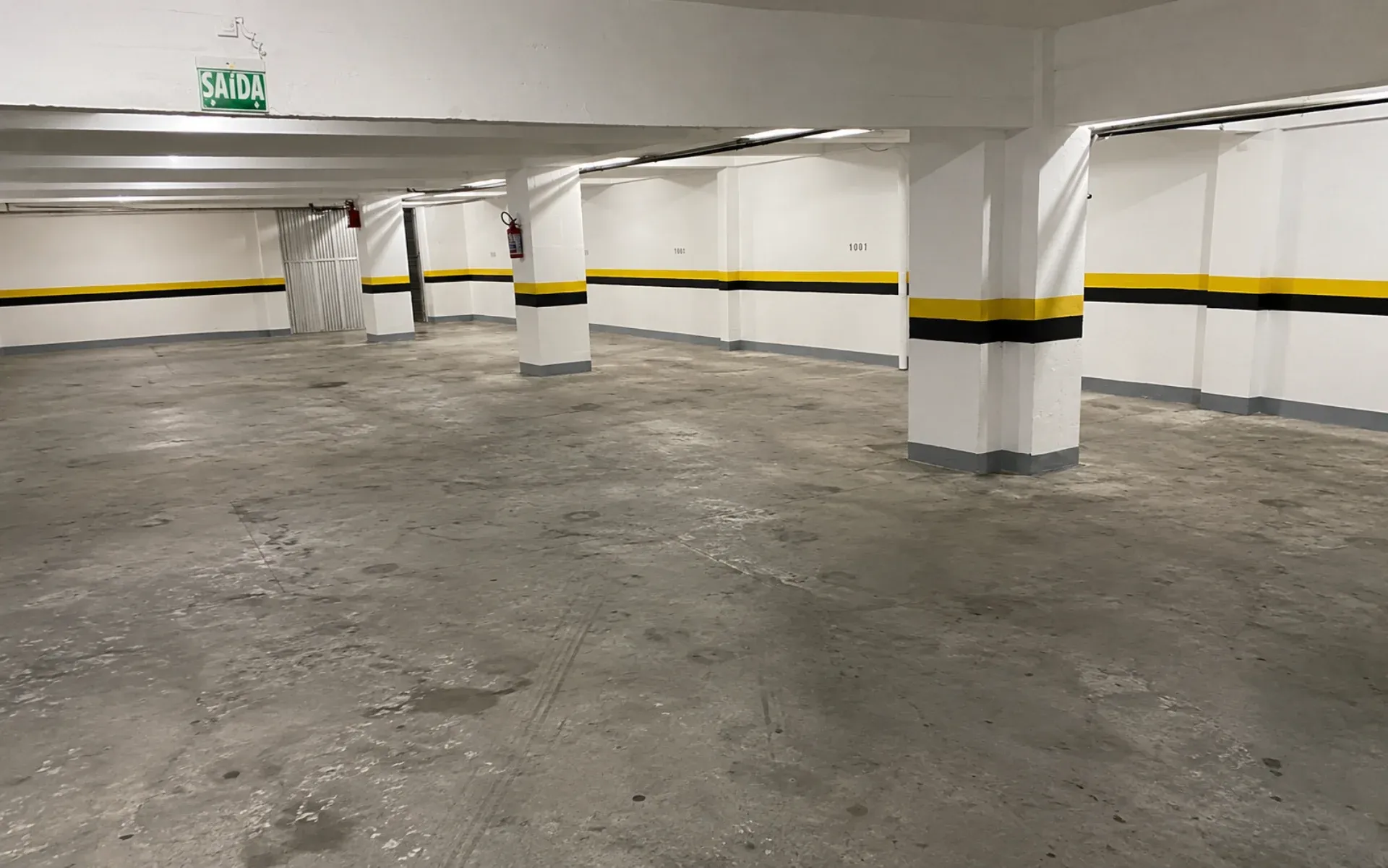 Estacionamento subterrâneo com piso de concreto degradado e manchas antes da aplicação do sistema epóxi Hazzin